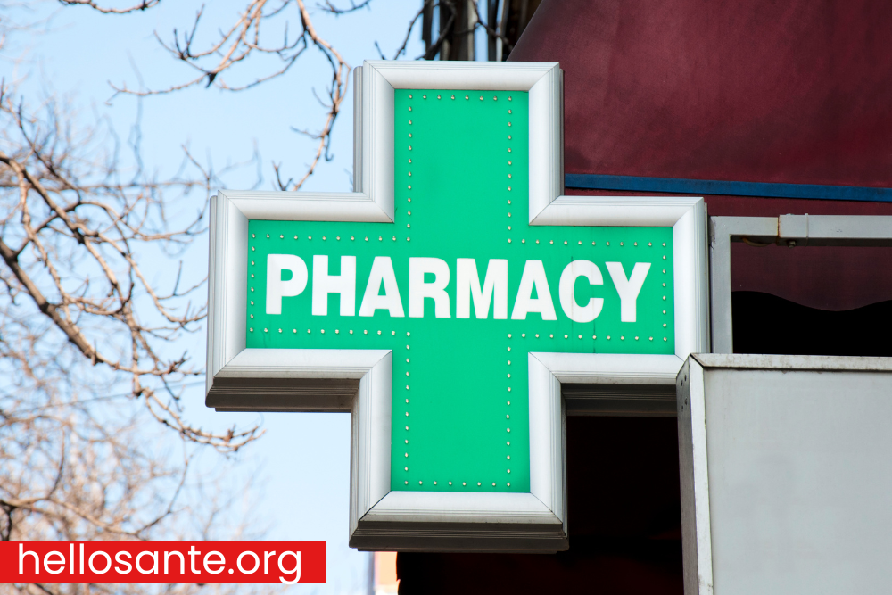 Green cross pharmacy sign hanging outside pharmacy building